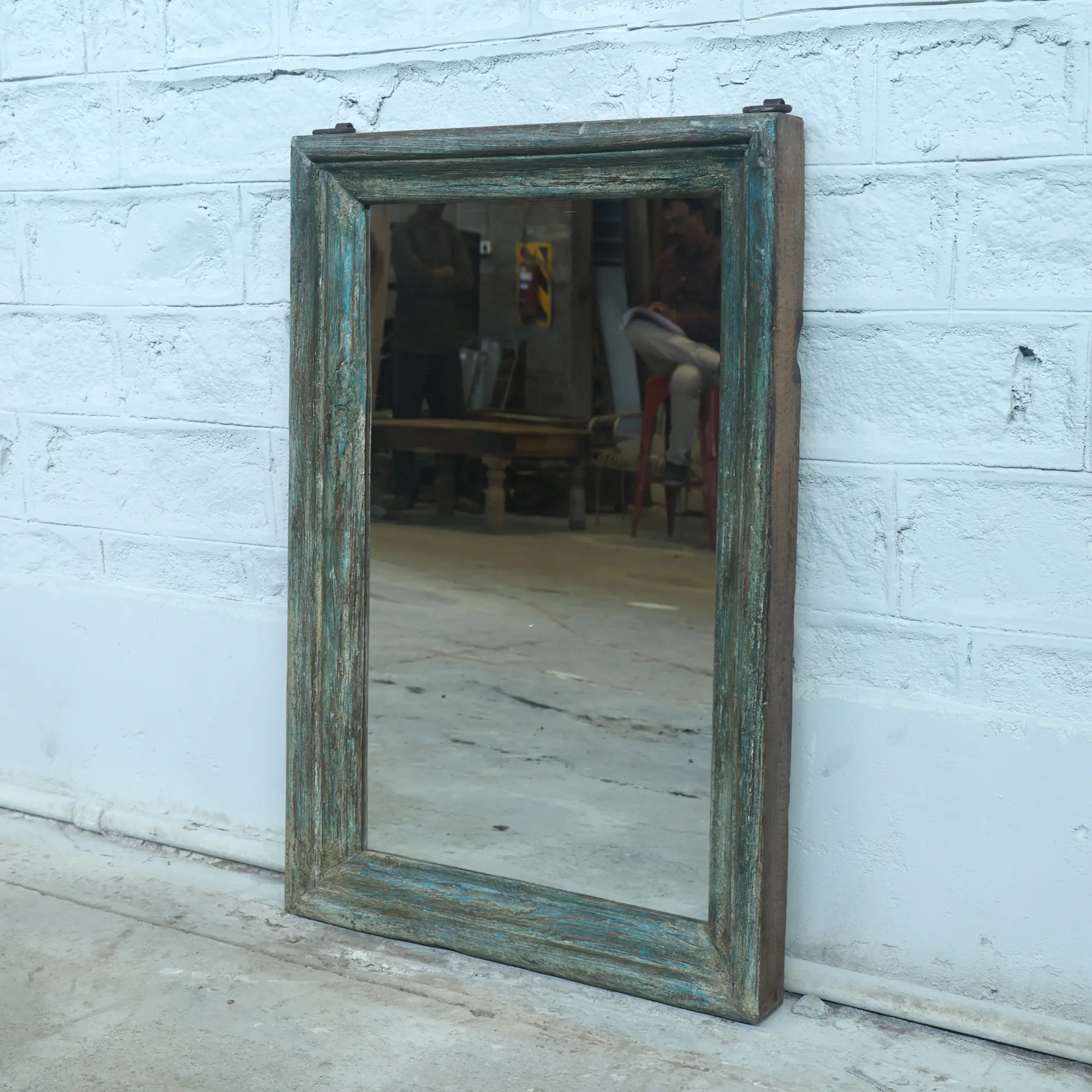 This vintage teak mirror stands out with its unique faded blue patina. The worn finish adds character and a sense of history