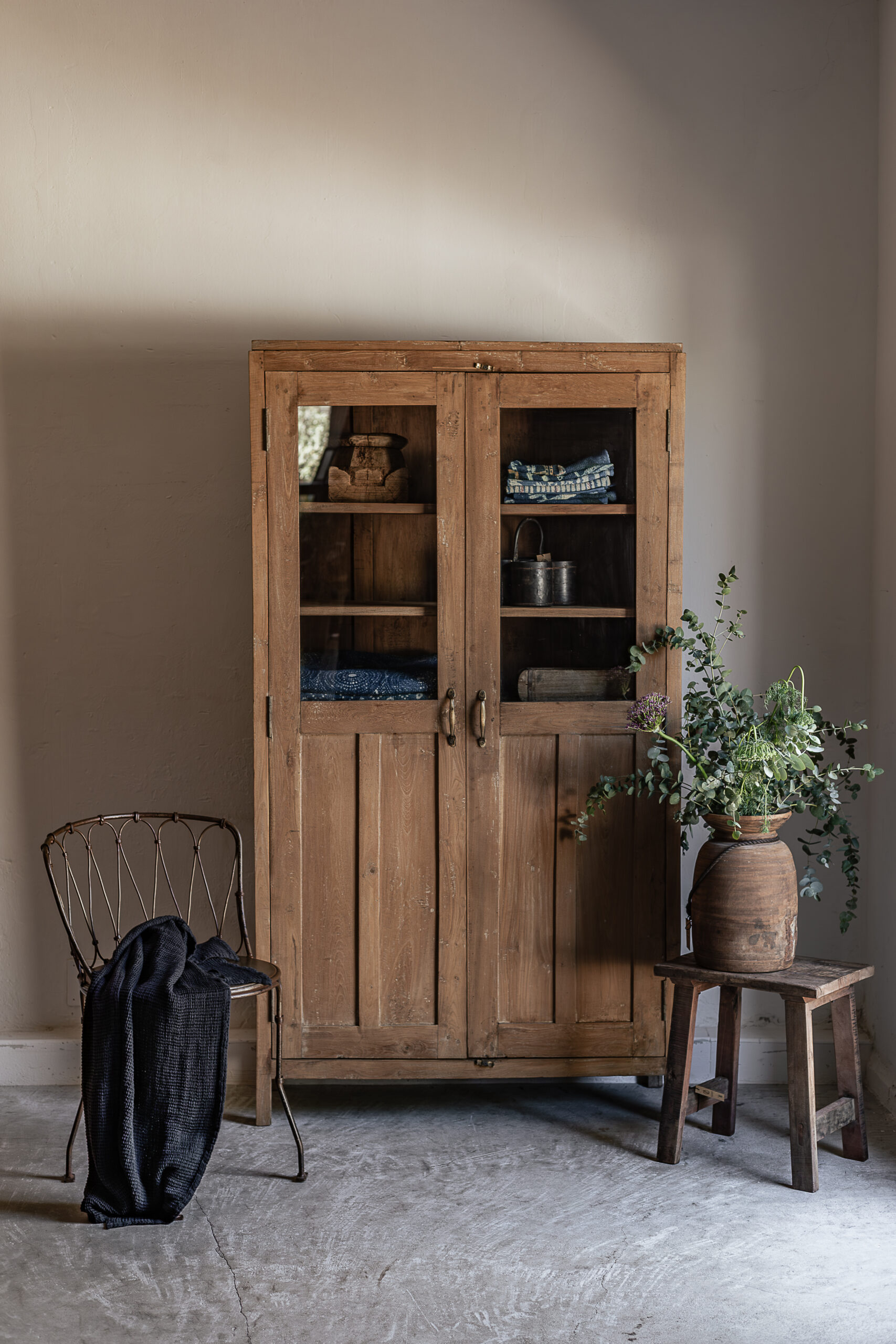 Vintage teak wardrobe with solid panel doors and brass handle, styled with vintage trunk and eucalyptus — Soulosofie Mallorca