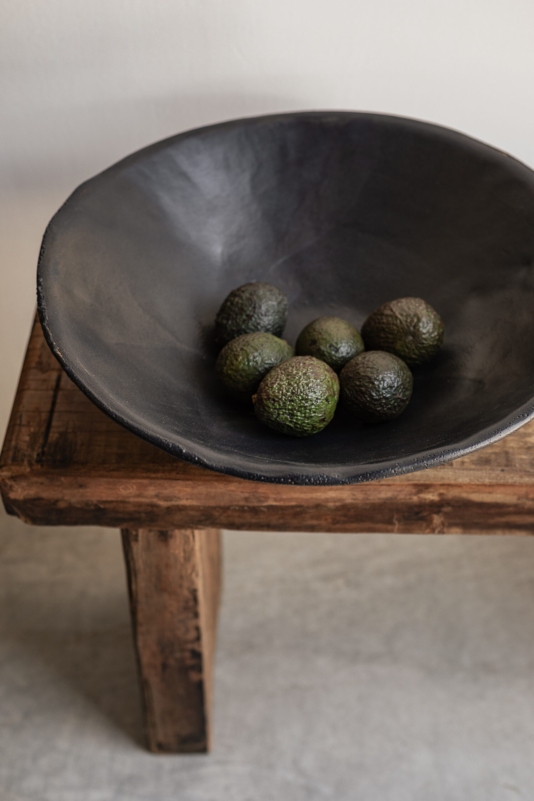 Large handmade black stoneware bowl by Badass Ceramics with raw organic rim, styled on reclaimed wood bench — Soulosofie Mallorca