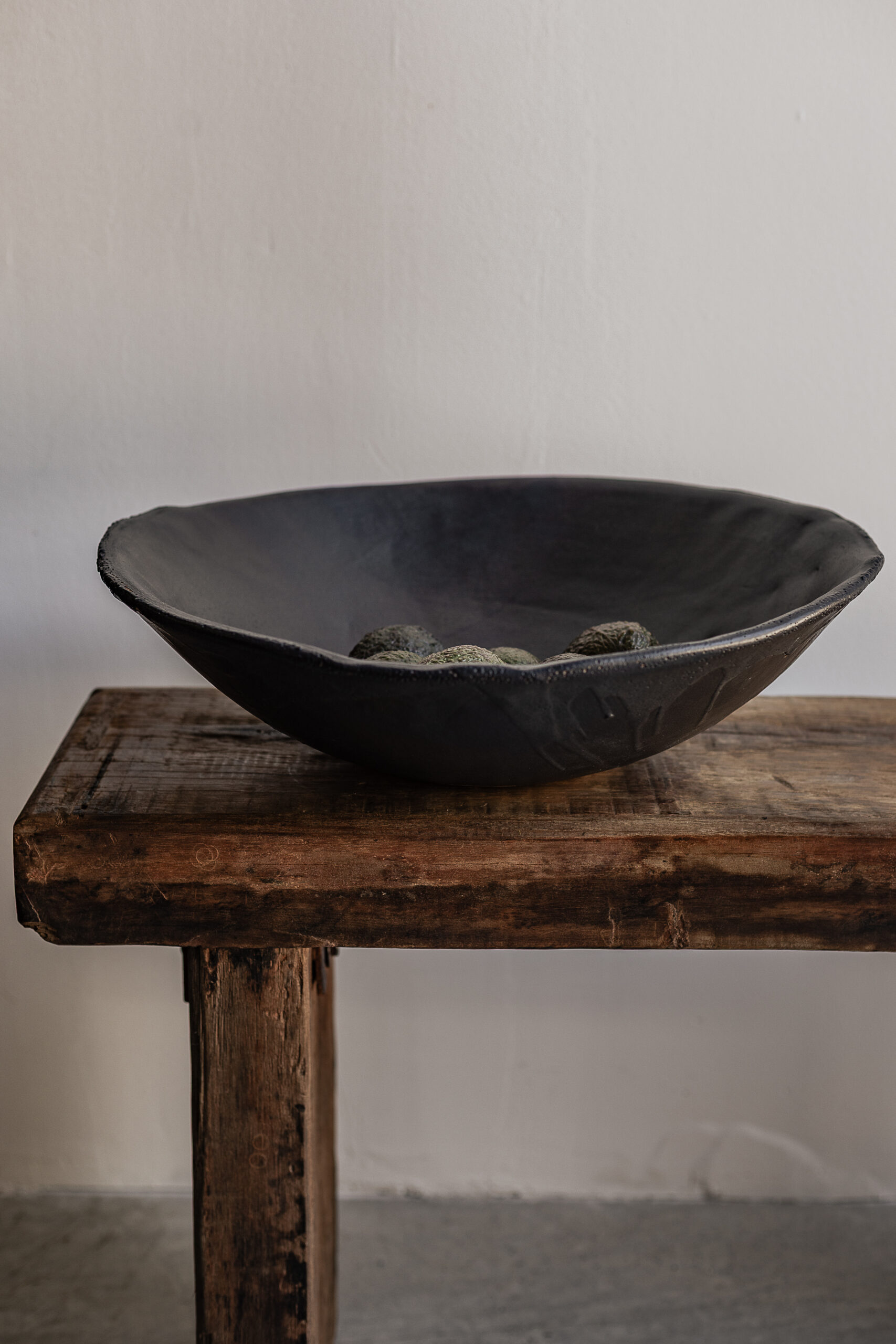 Large handmade black stoneware bowl by Badass Ceramics with raw organic rim, styled on reclaimed wood bench — Soulosofie Mallorca