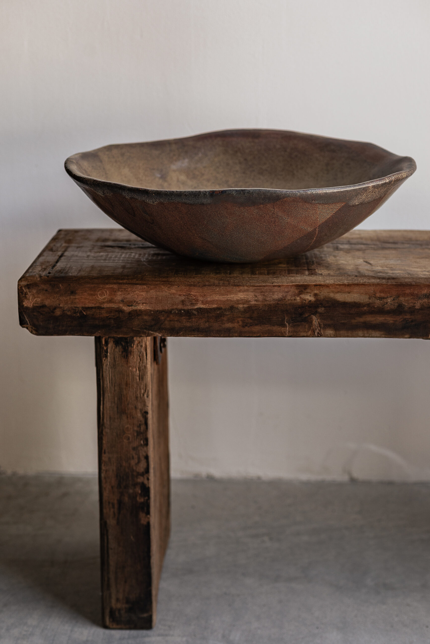 Large handmade rust brown stoneware bowl by Badass Ceramics with raw organic rim, styled on reclaimed wood bench — Soulosofie Mallorca