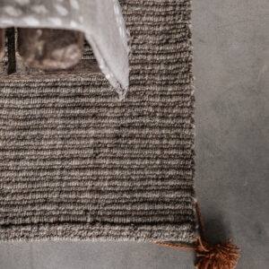Handwoven wool carpet in natural beige with tassel detail, textured weave close-up — Soulosofie Mallorca