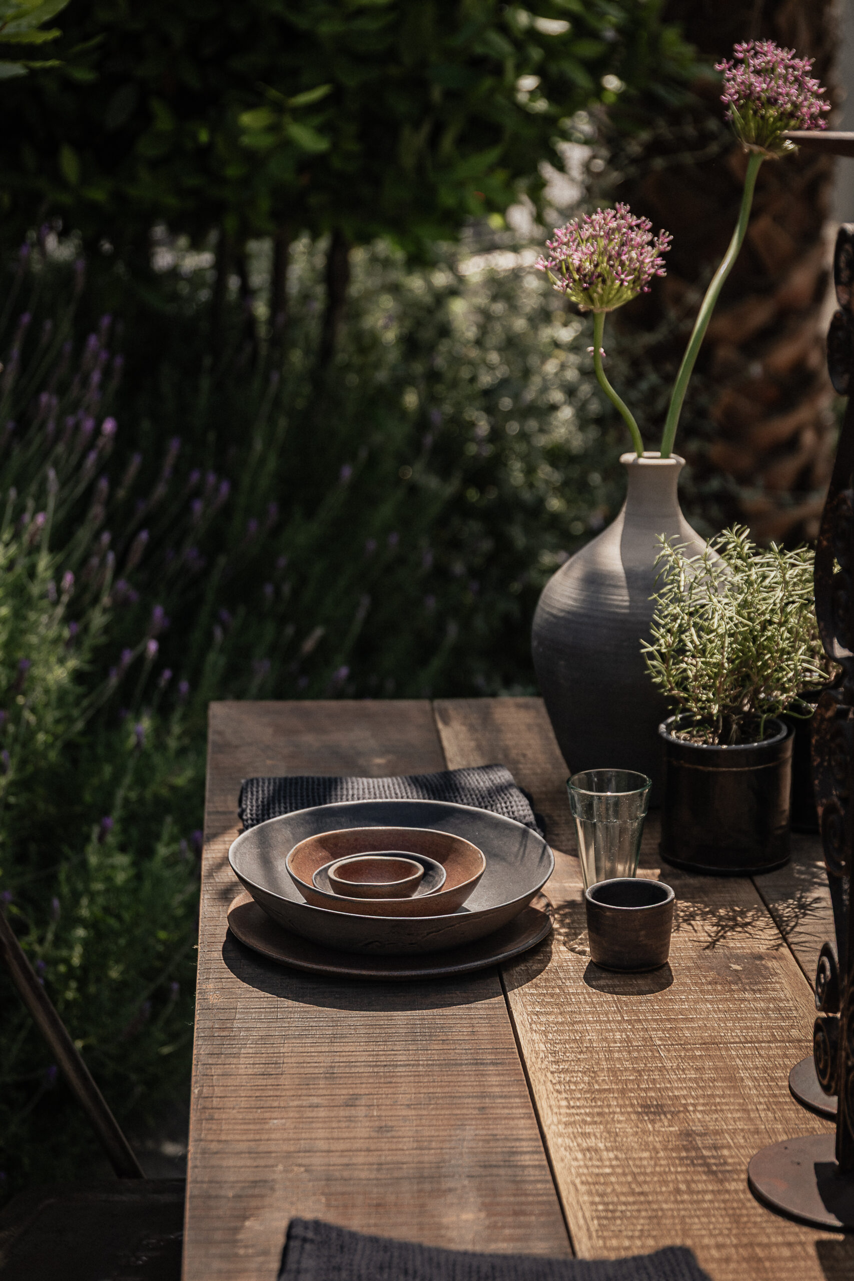 Reclaimed wood outdoor dining table surrounded by lavender garden, styled with handmade ceramics and stoneware vase — Soulosofie Mallorca