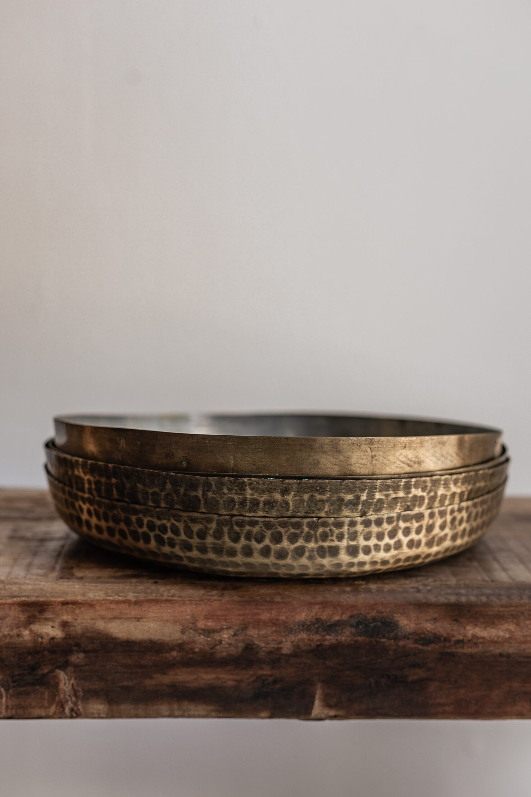 Vintage round hammered brass tray with warm patina finish, stacked set on reclaimed wood — Soulosofie Mallorca