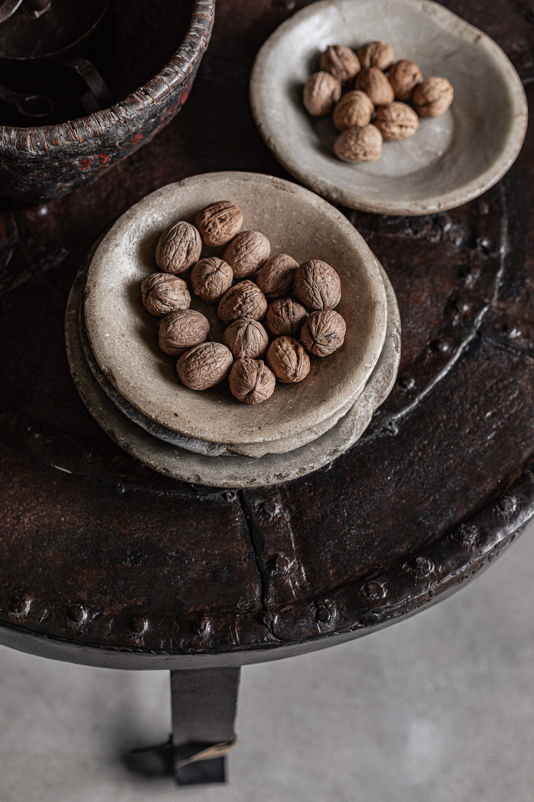 Vintage round iron coffee table with rustic riveted detail, styled with stone plates — Soulosofie Mallorca