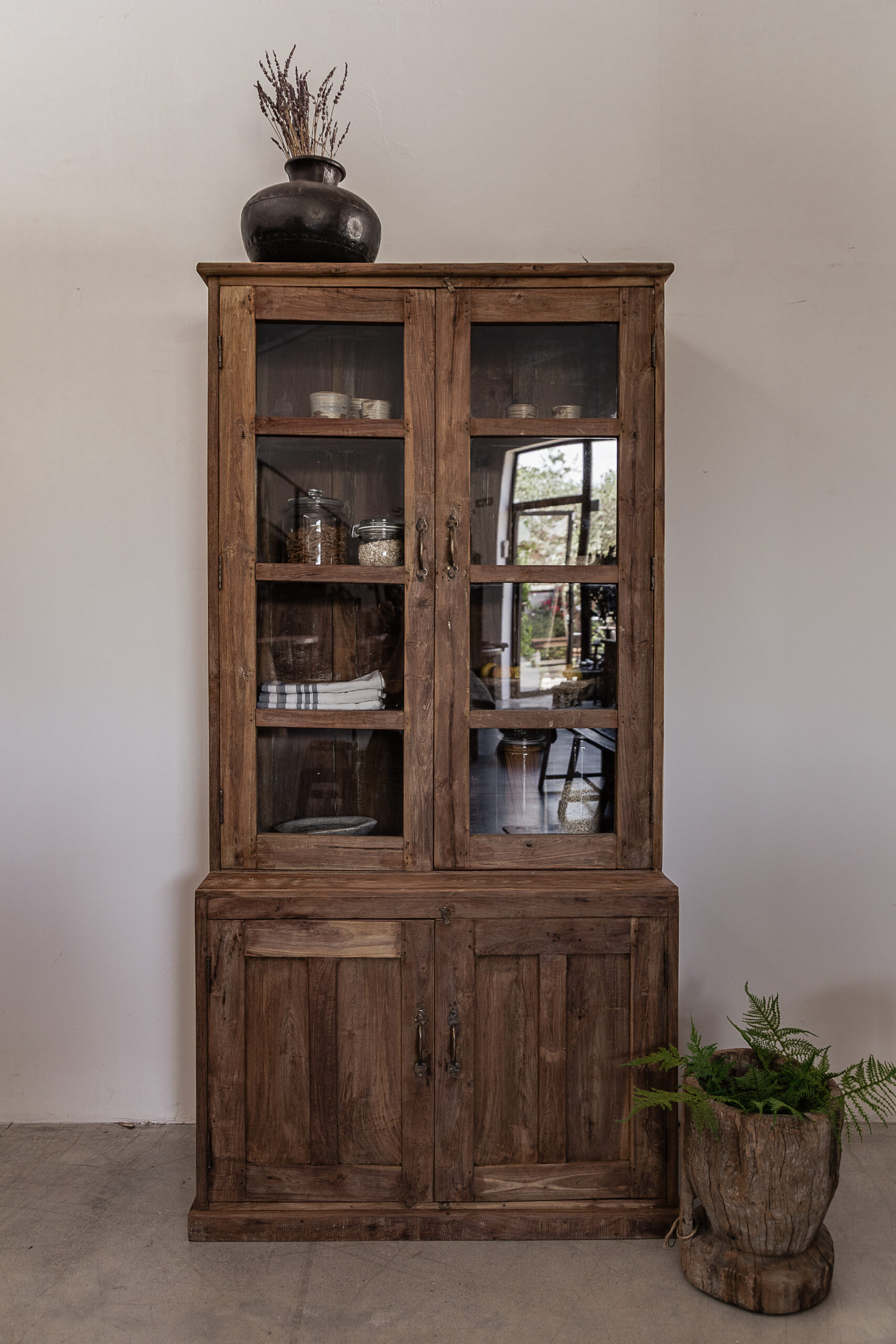 Vintage teak display cabinet with glass panel doors and solid lower cupboard, styled with ceramics and green glassware — Soulosofie Mallorca