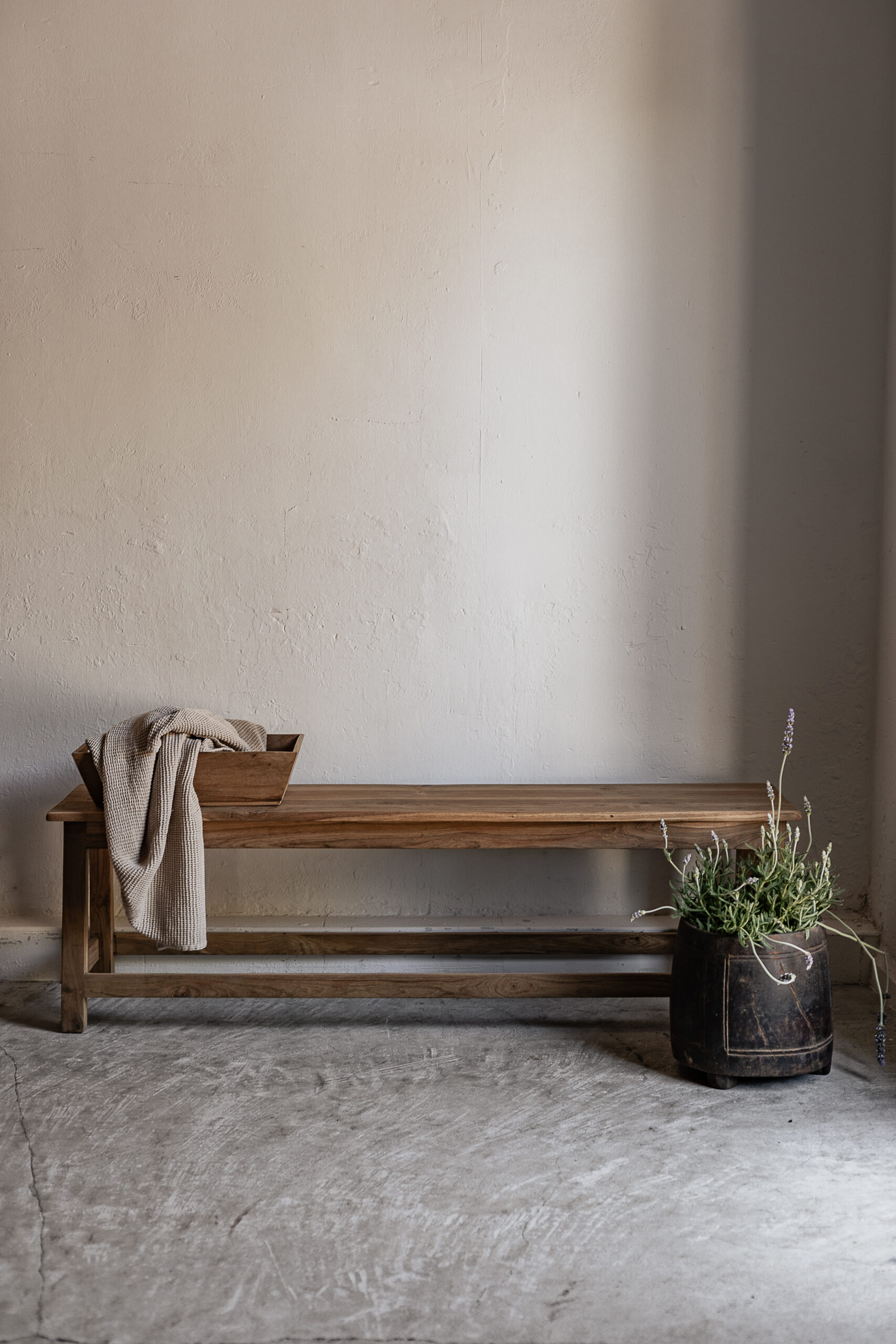 Long vintage teak bench with natural warm grain finish, styled with linen throw and lavender — Soulosofie Mallorca