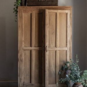 Vintage teak wardrobe with solid panel doors and brass handle, styled with vintage trunk and eucalyptus — Soulosofie Mallorca