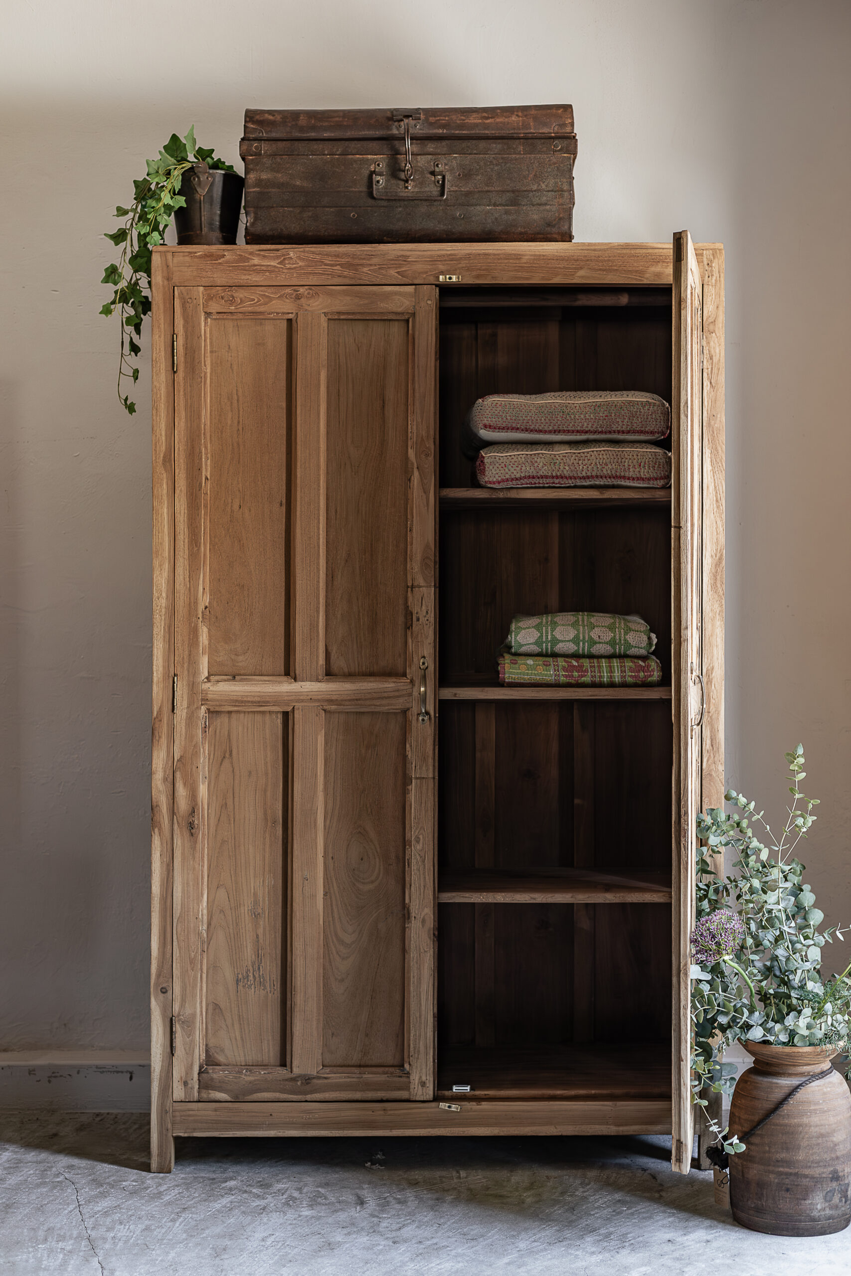 Vintage teak wardrobe with solid panel doors and brass handle, styled with vintage trunk and eucalyptus — Soulosofie Mallorca